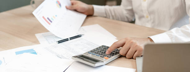 istock A man uses a calculator to calculate company profits from statistical graphs. Business men looking at charts, spreadsheets, bank accounts, statistics, economy, data analysis, stock exchange 1488353121