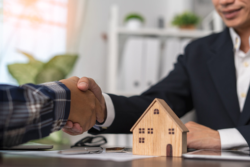 The real estate agent shakes hands with the client after agreeing to a contract for the sale of the home or insurance with legal effect. Success in house trading negotiations. Home or land mortgage