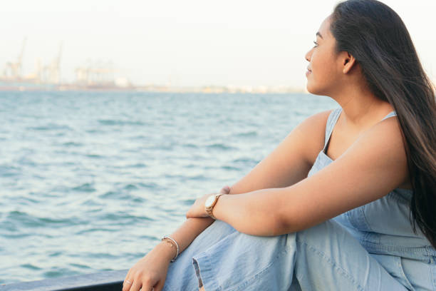 istock Young woman sits on a pier, pensive on a summer day. 1488353424