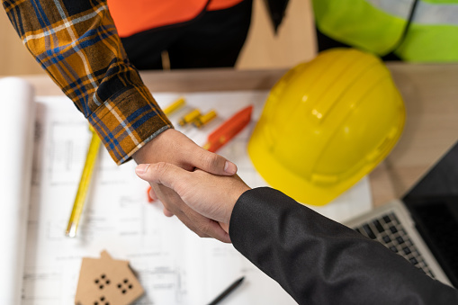 Real estate agent shakes hands with construction team leader. Business agrees to sign a home builder after engineer shows model Building project. Mortgage, rent, buy, sell, purchase,move,Selling home.