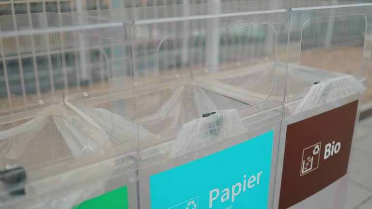 Close up of a woman hand throwing trash into paper bin at the city train station