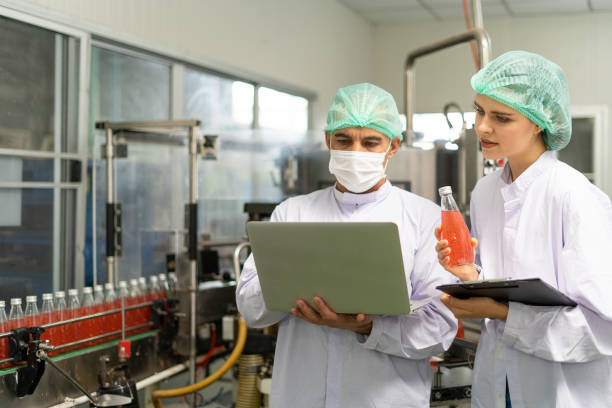 istock Quality control engineer holds computer to work with female worker. Workers in the factory write down notes about bottles or gallons before send to customers. Inspection quality control. 1488358048