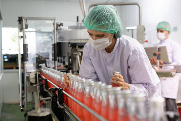 Food and Drug Quality Supervisors inspect quality in factory. Staff wear masks and helmets for cleanliness and safety in drinking water and drug production lines during the COVID 19 outbreak. los supervisores de calidad de alimentos y medicamentos inspeccionan la calidad en la fábrica. el personal usa máscaras y cascos para la limpieza y seguridad en las líneas de producción de agua potable y medicamentos durante el brote de covid 19.