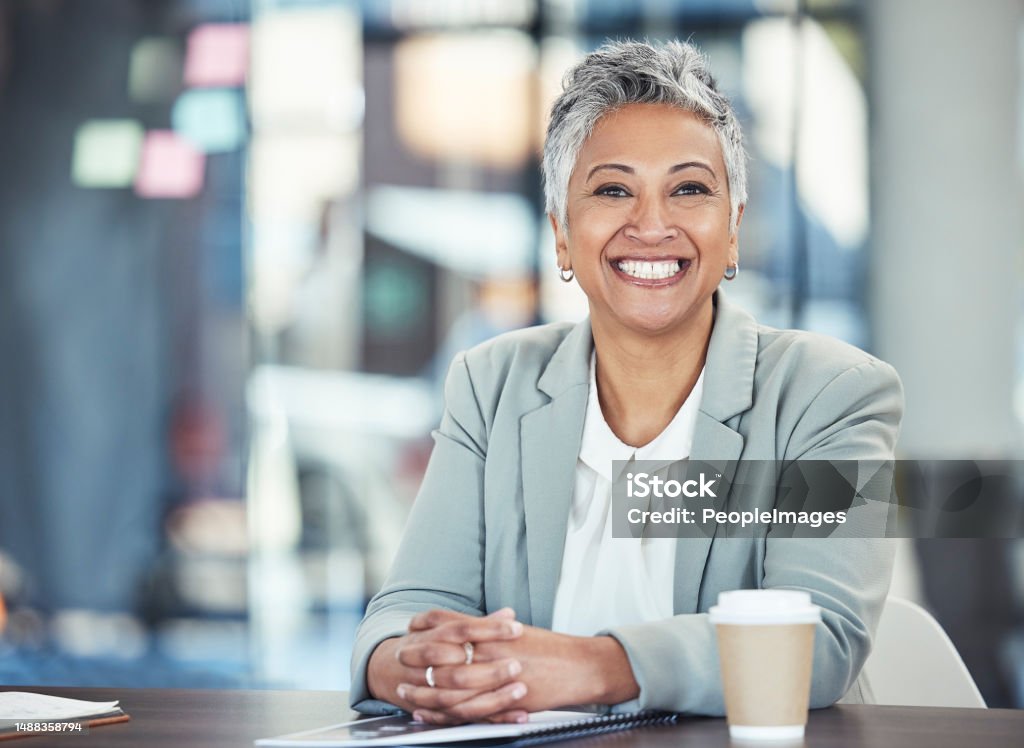 Ready, business and portrait of a woman in corporate for working, success and goals. Smile, happy and mature office employee sitting at a desk to start work in the morning at a legal company Businesswoman Stock Photo