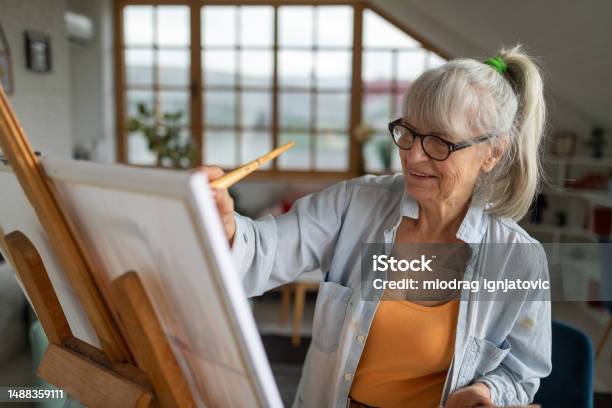 Senior Woman Painting On A Canvas In Her Apartments Living Room Stock Photo - Download Image Now