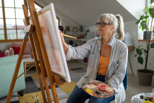 아파트 거실에서 캔버스에 그림을 그리는 노인 - painted image paintings oil paint senior women 뉴스 사진 이미지