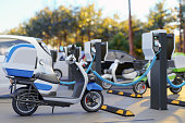 Clean Energy Concept. Close-up View Of Charging Electric Motorcycle In Parking Lot