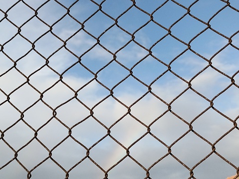 A View of the Clouds Behind the Iron Net. Clear Sky In The Afternoon.