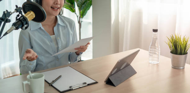 istock Bright Asian women record a podcast with a microphone and computer camera. A young woman work from home studio. broadcast studio concept 1488362503
