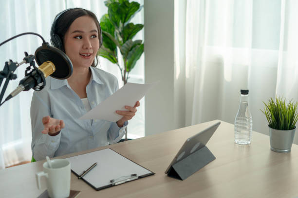 istock Bright Asian women record a podcast with a microphone and computer camera. A young woman work from home studio.  broadcast studio concept 1488362507