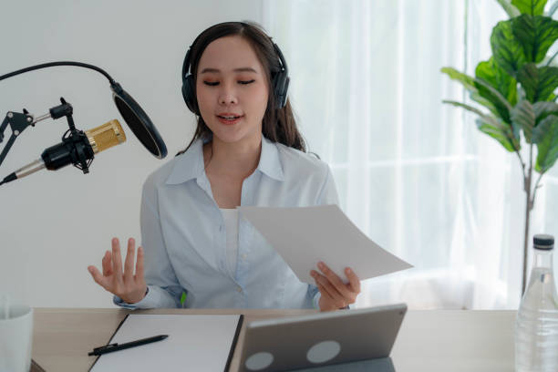 istock Bright Asian women record a podcast with a microphone and computer camera. A young woman work from home studio. broadcast studio concept 1488362515