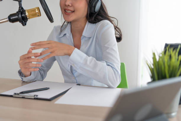 istock Bright Asian women record a podcast with a microphone and computer camera. A young woman work from home studio. broadcast studio concept 1488362523