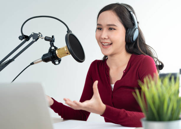 istock Bright Asian women record a podcast with a microphone and computer camera. A young woman work from home studio.  broadcast studio concept 1488362530