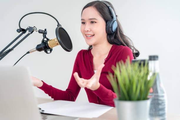 istock Bright Asian women record a podcast with a microphone and computer camera in studio. Online radio for entertainment air sign and communication. broadcast studio 1488362551