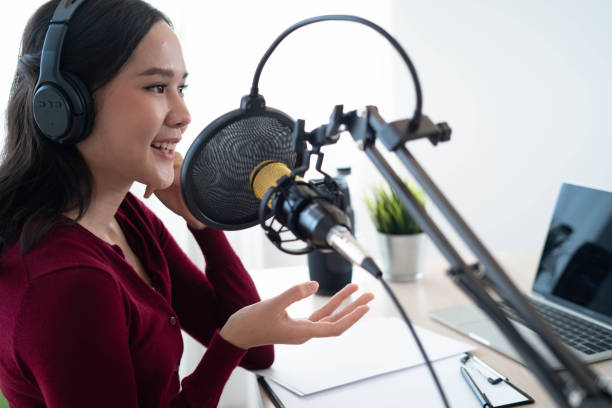 istock Bright Asian women record a podcast with a microphone and computer camera. A young woman working from a home studio 1488362567