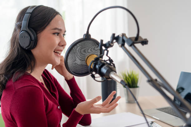 istock Bright Asian women record a podcast with a microphone and computer camera. A young woman work from home studio. broadcast studio concept 1488362593