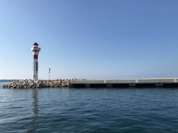 istock a small lighthouse on a beach with a pier in the distance 1488364197