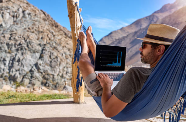 digital nomad mature man in a lying in a hammock with a laptop