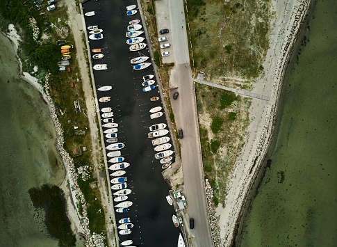 An aerial shot of a port in Denmark, featuring several moored boats in the harbor waters