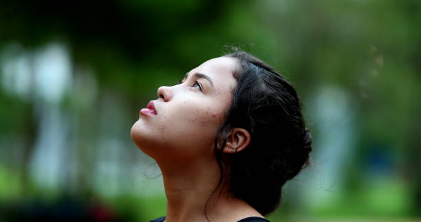 Young woman close-up face looking at sky. Pensive girl stock photo