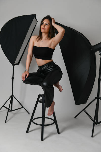istock Beautiful Confident Female In Leather Pants Posing Among Lightning During Studio Shot 1488369969