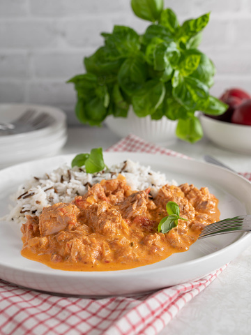 Delicious fish dish with canned tuna, wild rice and basmati rice. Served with a delicious vegetable cream sauce on a plate on light kitchen background. Front view