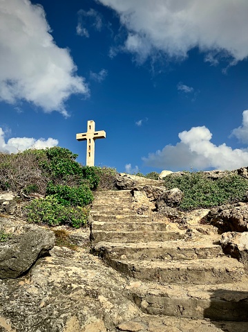 Stone staircase going up to a religious cross in the nature of the French West Indies. Photo taken in Guadeloupe in January 2023