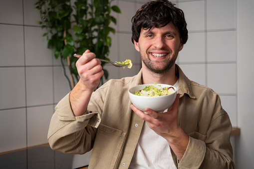 Man in a beige shirt, eating a vegetable salad for lunch, the concept of healthy eating and lifestyle.