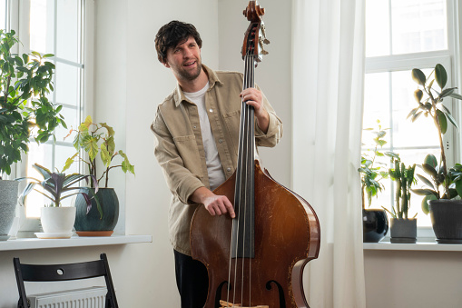 View of a musician playing the double bass in the living room. Musical instrument.