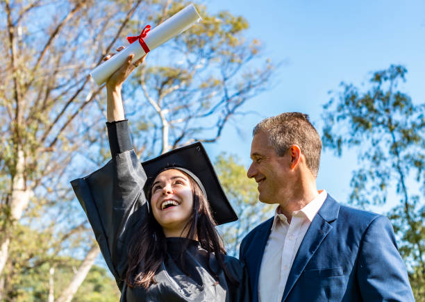 menina feliz abraçando seu pai enquanto olhava para seu diploma no dia de sua formatura. - satisfaction clothing argentina smiling - fotografias e filmes do acervo