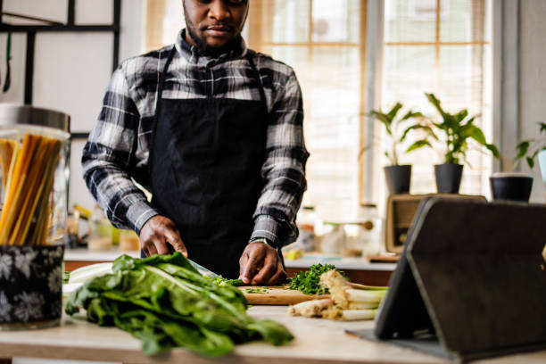 istock Hands of African-American chef who cutting vegetables while using digital tablet 1488375135