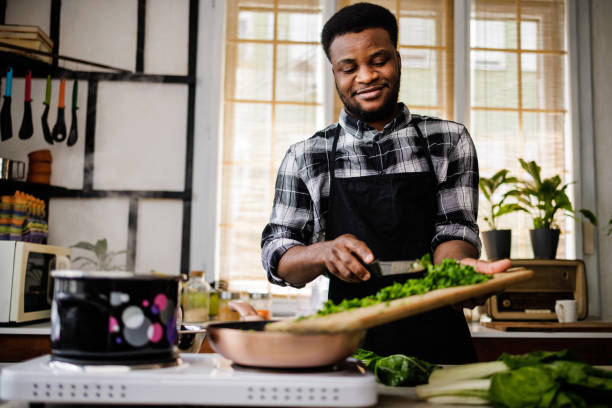 istock Smiling man puts vegetables in pan for frying 1488375194