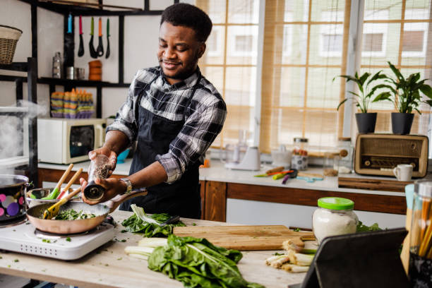 istock Smiling chef puts spices in frying pan 1488375399