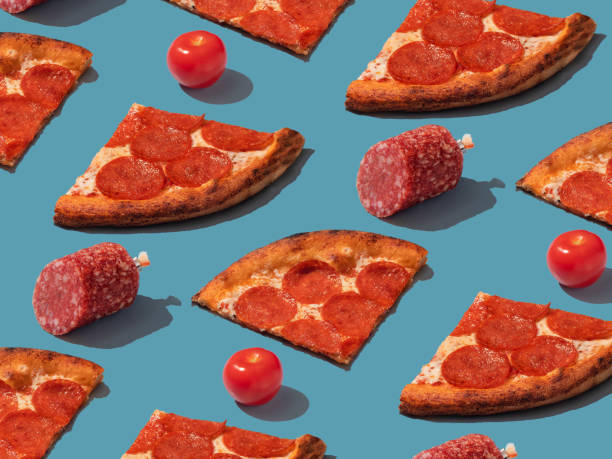 istock Pepperoni slice pizza with salami and tomatoes pattern. Food pattern with hard shadows 1488376176