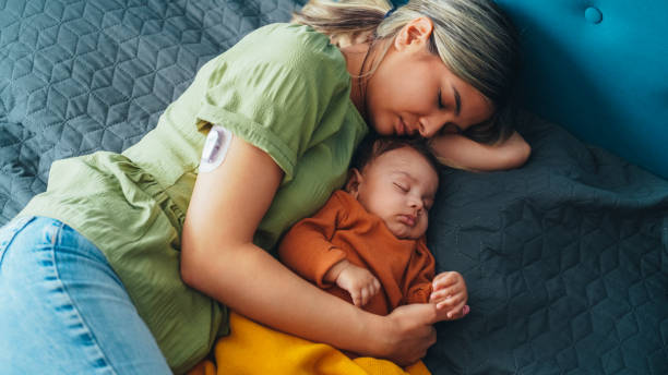 Young mother with diabetes and baby napping at home stock photo