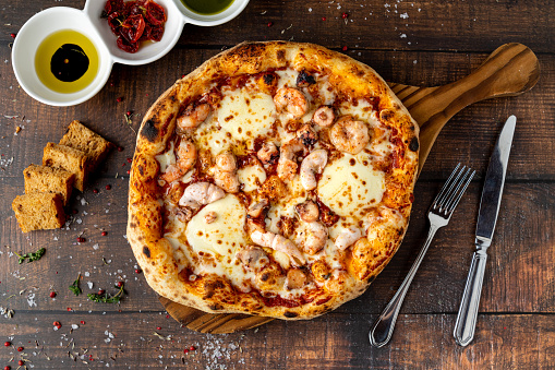 Italian pizza with shrimp and mozzarella on a cutting board