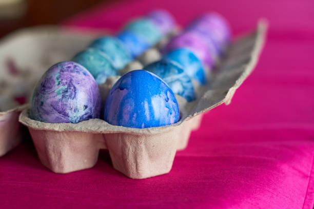 istock Carton of easter eggs on pink silk. 1488379536