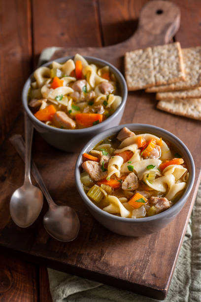 Chicken Noodle Soup Bowls of Homemade Chicken Noodle Soup with Crackers cooked selective focus vertical pasta stock pictures, royalty-free photos & images