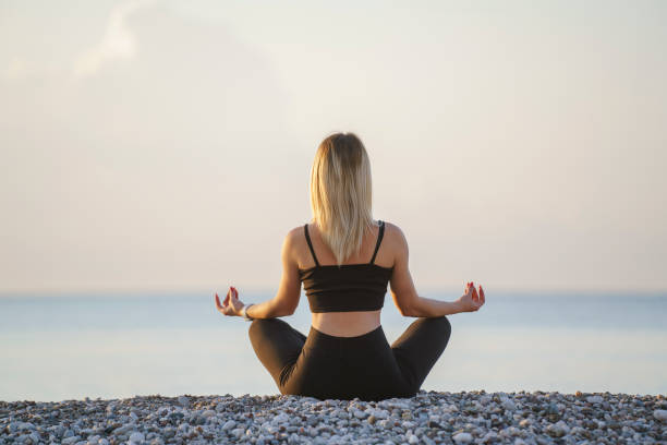 istock Young woman practicing yoga, meditating on the beach 1488381677