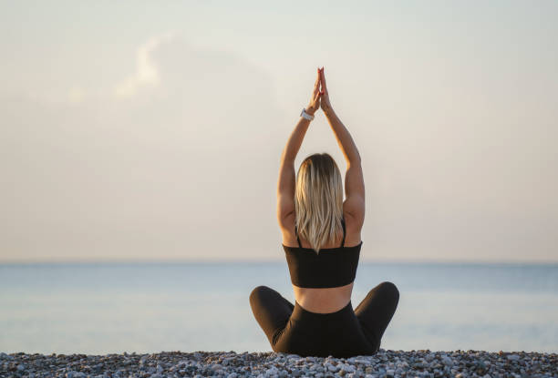 istock Young woman practicing yoga, meditating on the beach 1488381686