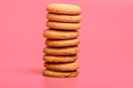 Buttery round homemade baked biscuits stacked on top of each other on a pink background