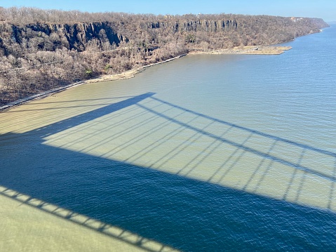 Shadow of the suspension cables of the George Washington Bridge, carrying I-95 and US 1/9 between New Jersey and New York City in New York State, on the Hudson River on a sunny day