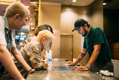 Asian senior couple choosing a movie and buying movie tickets at the ticket counter.