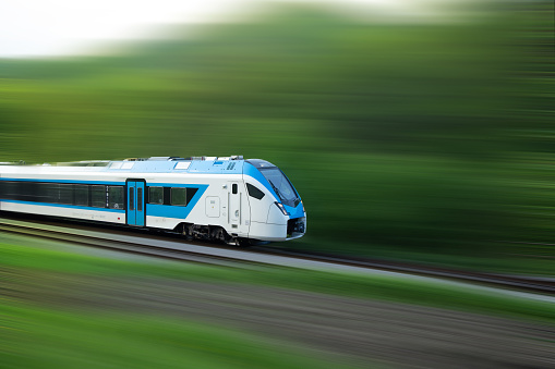 Speeding passenger train with motion blur against green countryside