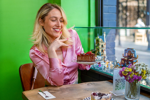 Woman admiring delicious dessert in city cafe