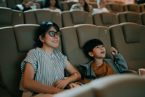The Asian family is happy as they bring their son to watch their favorite movie, and the boy is very happy.