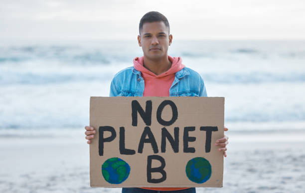 Save earth, sign and man protest at beach pollution, environment and green, eco planet. Ocean, sea and portrait of person with nature globe poster for awareness, global warming and climate change Save earth, sign and man portrait at beach pollution, environment and green, eco planet protest. Ocean, sea and angry person with nature globe poster for awareness, global warming and climate change walking beach women sadness stock pictures, royalty-free photos & images