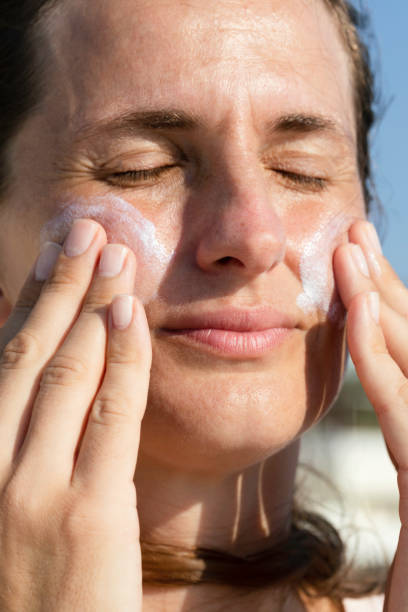 istock Woman is applying sun cream on her face 1488398776