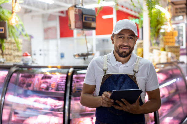 Happy man working at the butcher's shop using a tablet computer