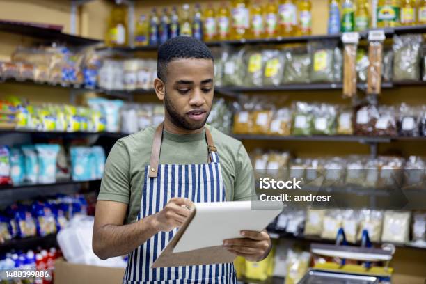 Grocer Working At A Local Food Shop Doing An Inventory Stock Photo - Download Image Now